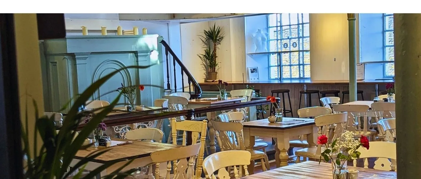 Inside The Chapel Cafe, Port Isaac — original chapel interior with cream chairs, tables and natural light from arched windows
